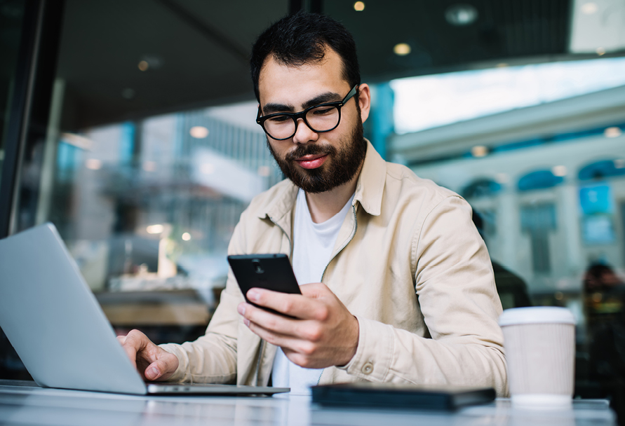 Man using computer and checking mobile phone