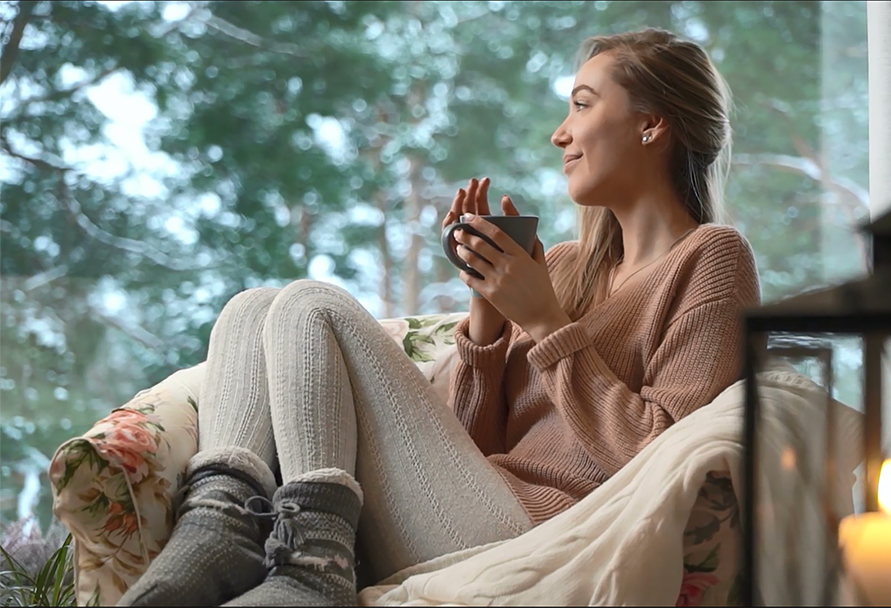 Woman holding a mug and looking outside at the snow