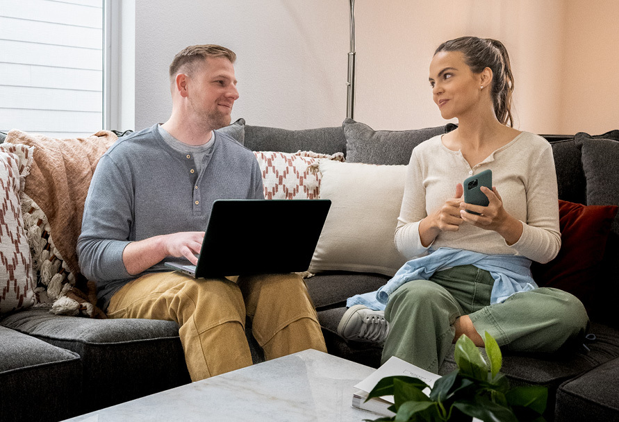 Mike and Maria from Team Ready sitting on a couch using their laptop and cell phone