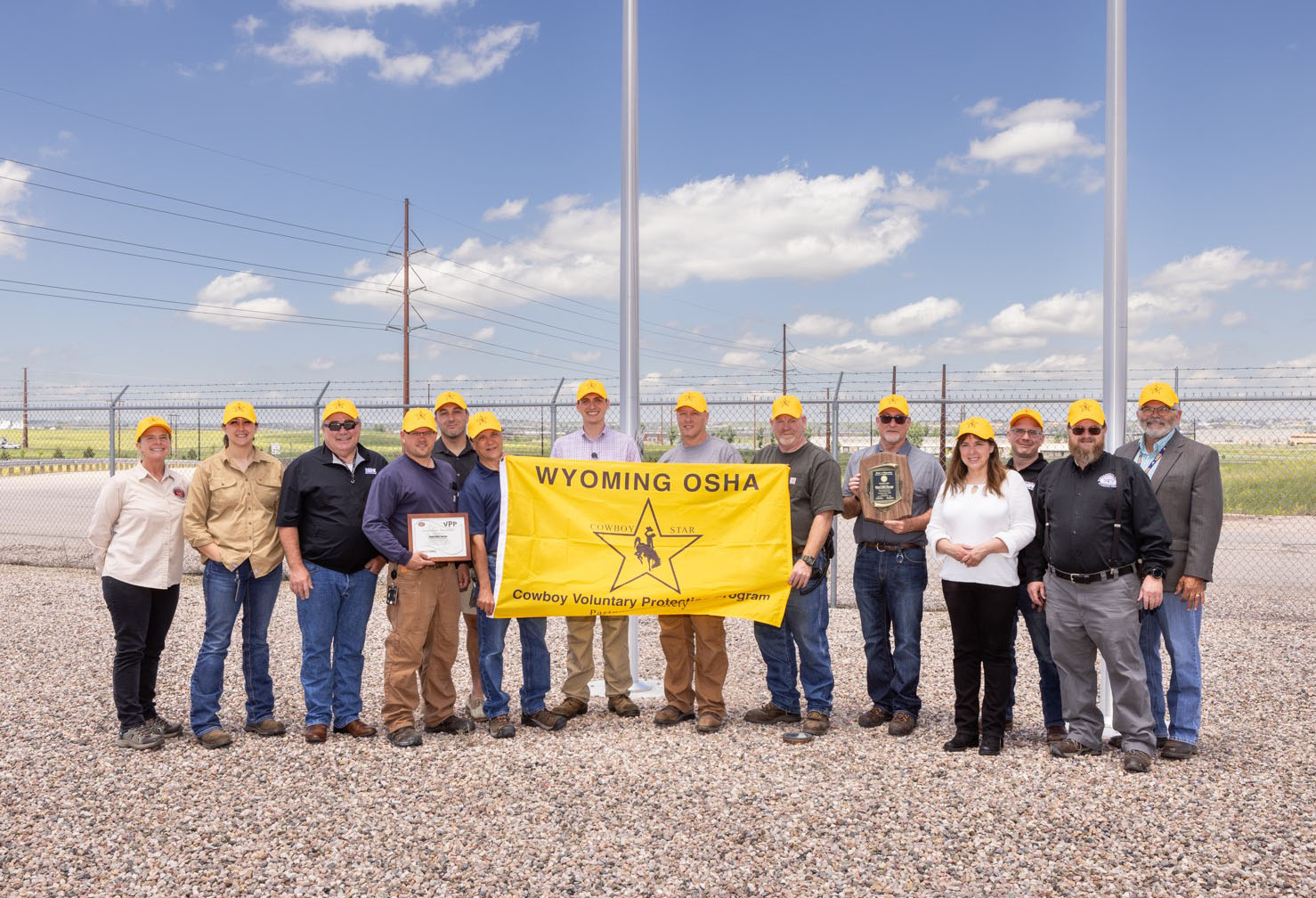 group of people posing with flag outside of cheyenne prairie generating station