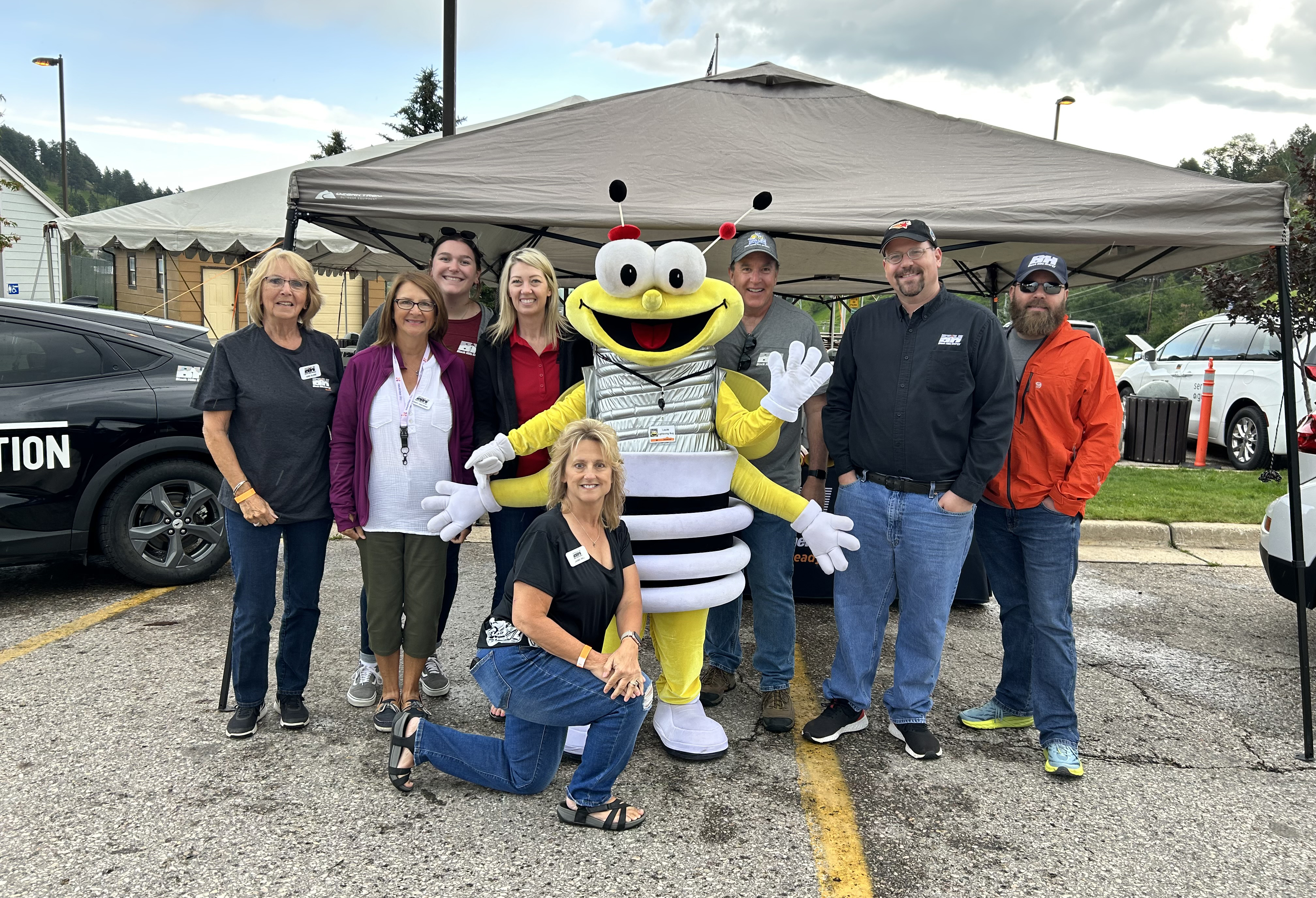 group of people posing with louie the lightning bug