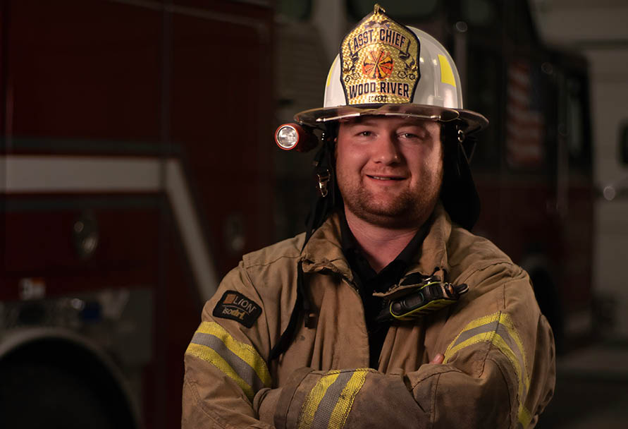 Volunteer firefighter posing in front of a firetruck
