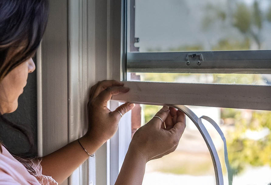 Installing weather stripping on a window.