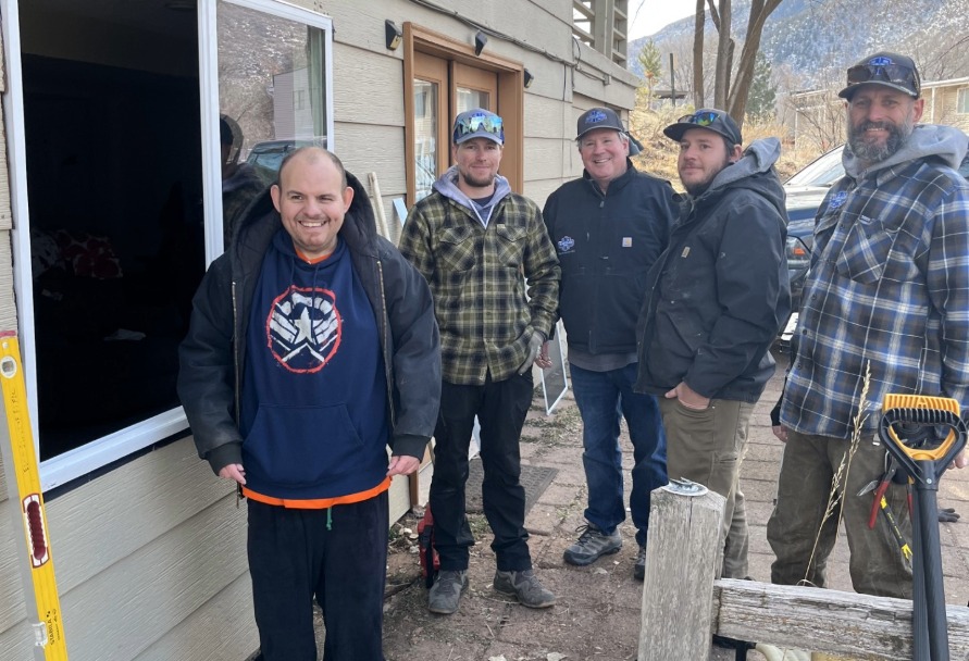 Five people posing near a house with new windows