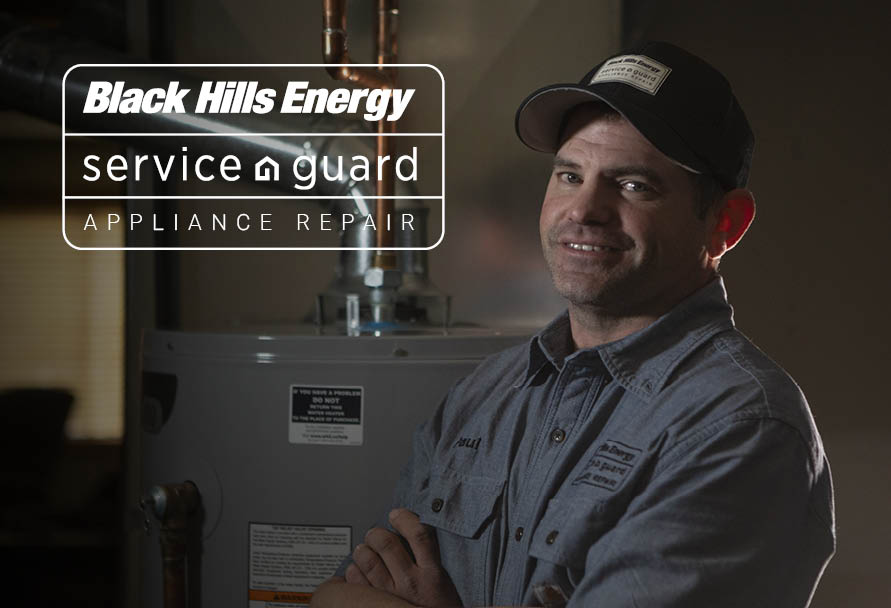 Appliance technician posing next to a water heater