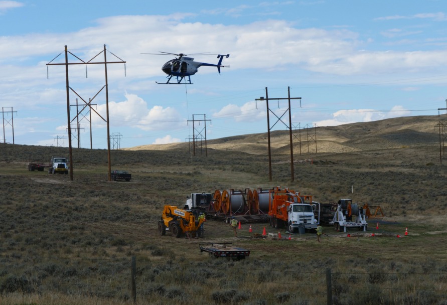 Helicopter and service trucks working on new transmission lines