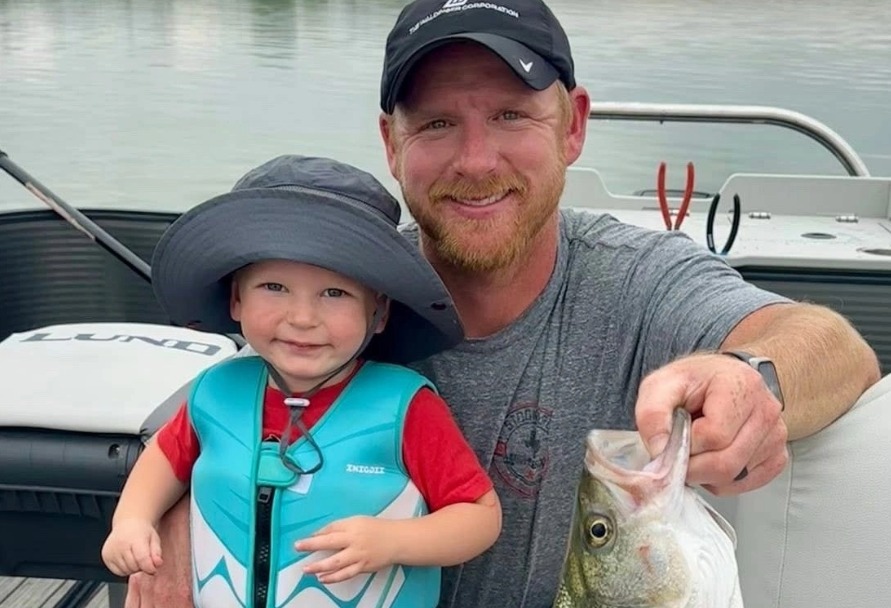 Father and son pose for a photo with a fish they caught