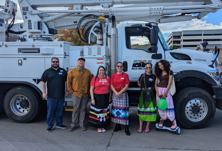 Black Hills Energy employees posing for a photo in front of a bucket truck during the Indigenous Peoples Day Parade in Rapid City, South Dakota