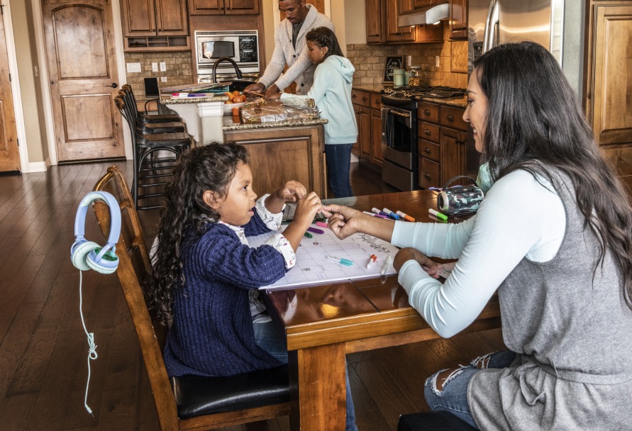 Family in the kitchen with mom and daughter sitting at the table in the foreground