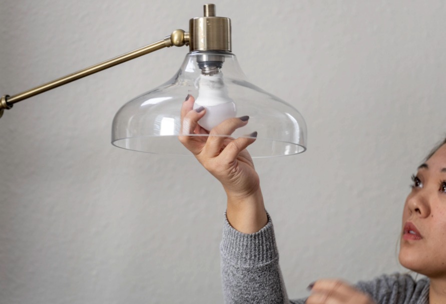 close up of woman changing a lightbulb in a lamp