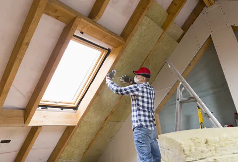 Man in plaid shirt insulating a ceiling
